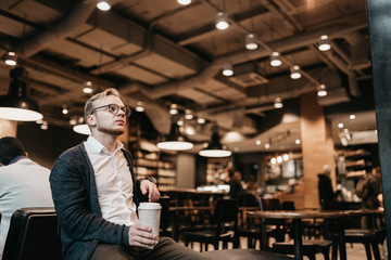 European man blond in a cafe with a glass of coffee enjoys the day.