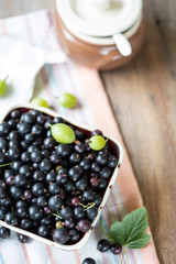 Blackcurrants in the ceramic bowl on a wooden table
