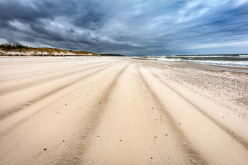 Sandy beach on stormy day by the sea.