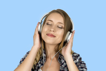 Fototapeta premium beautiful young woman listening music in headphones isolated blue background