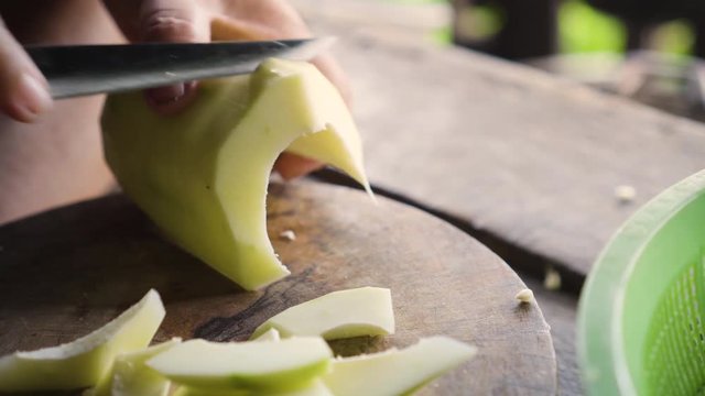 Old lady using knife to cut a winter melon to pieces. Ingredient for cooking