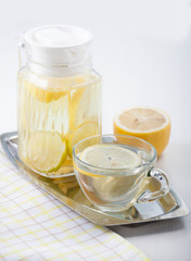   Lemon water in a glass jug and in a glass cup