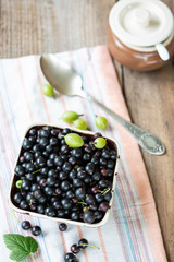 Blackcurrants in the ceramic bowl on a wooden table