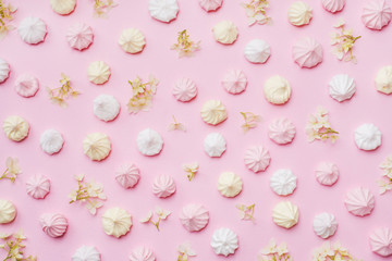 Colored small meringues on a pink background. Flat lay concept. Copy space.