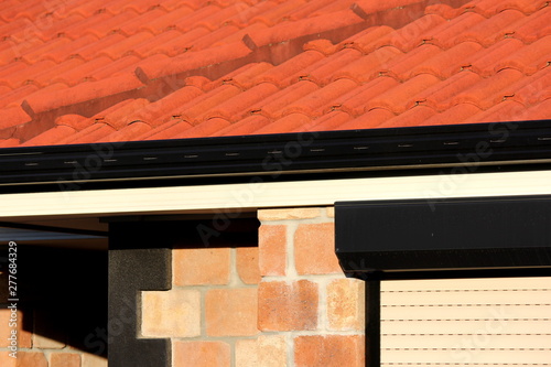 Abstract Terracotta roof with sandstone bricks and black trim
