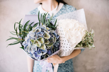Very nice young woman holding beautiful tender blossoming mono bouquets of fresh white and blue...