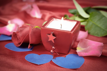 candle and rose on red silk background