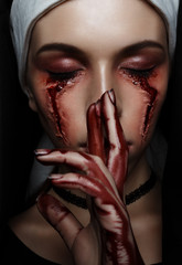 Dark beauty nun in burqa with black eyes with bloody stains and scars. Horror halloween concept of witch obsessed by the devil