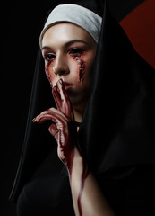 Dark beauty nun in burqa with black eyes with bloody stains and scars. Horror halloween concept of...