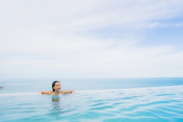 Fototapeta na wymiar Portrait young asian woman relax smile happy around outdoor swimming pool in hotel resort with sea ocean view