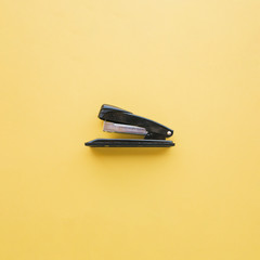 Black stapler on orange background