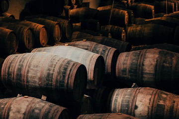 Wooden barrels with wine inside traditional winery with dark cellar for winemaking, Portugal
