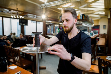 Preparing the shisha, aka nargile or hookah at a restaurant by placing the cup on top