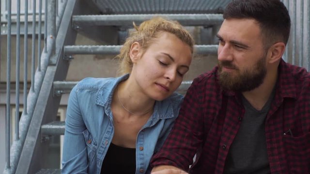 Couple Sitting On Fire Escape In House