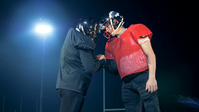 Pre-game greetings of two American football players at the night stadium