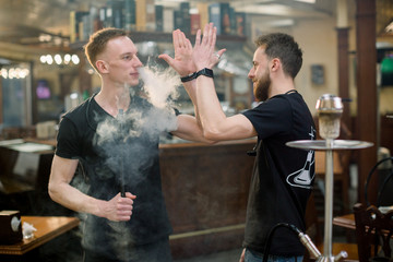 Two young hookah masters prepare the Shisha in traditional cozy cafe