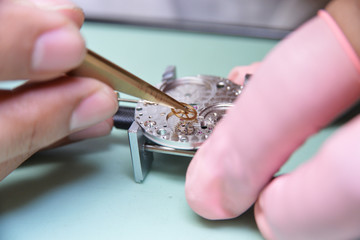 Watchmaker piced up the tiny escape wheel part very carefully to mainplate