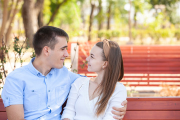 Fototapeta premium Young couple sitting on bench in park.