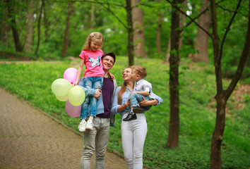 Fototapeta premium Happy young family with their two children are walking in summer forest park, parenthood vacations with kids