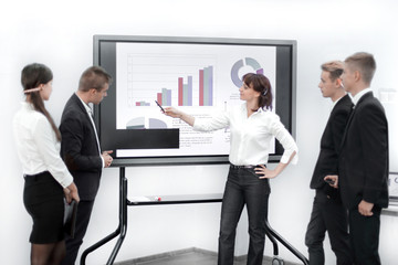 business team discussing the financial schedule, standing near the screen in the conference room.