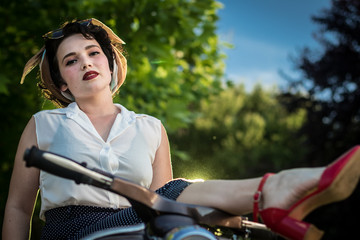Fototapeta na wymiar A pinup woman in a vintage dress sitting on a scooter.dng