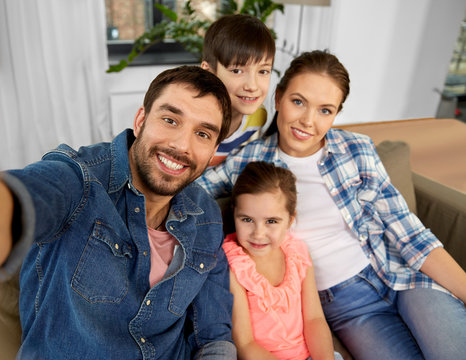 family and people concept - happy father, mother, little son and daughter taking selfie at home