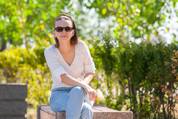 Young beautiful woman sitting on bench in park.