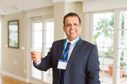 Middle age business man drinking a cup of coffee wearing identification card