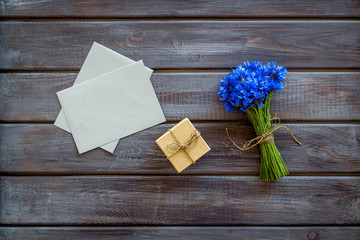 Summer design for blog with bouquet of blue cornflowers, envelope and gift on wooden background top view copyspace