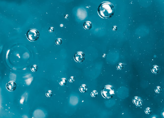 Bubbles of air on the smooth surface of blue water as an abstract background