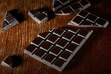 Chocolate bar and chunks on vintage wooden background. Sweet food photo concept