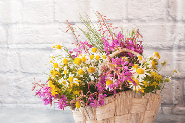 bouquet of beautiful wildflowers in a basket on a gray background with copy space.