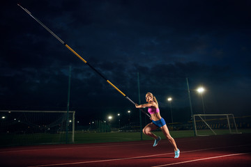 Ready to overcome difficulties. Professional female pole vaulter training at the stadium in the...