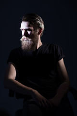 Fototapeta premium stylish bearded man in a black t-shirt sitting in a chair