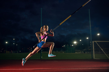 Ready to overcome difficulties. Professional female pole vaulter training at the stadium in the...