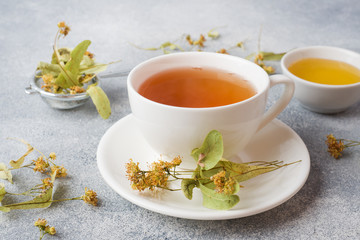 Cup of green tea and flowers linden on grey background. Copy space.