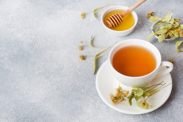 Cup of green tea and flowers linden on grey background. Copy space.