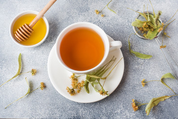 Cup of green tea and flowers linden on grey background. Copy space.