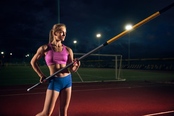 Ready to overcome difficulties. Professional female pole vaulter training at the stadium in the evening. Practicing outdoors. Concept of sport, activity, healthy lifestyle, action, movement, motion.