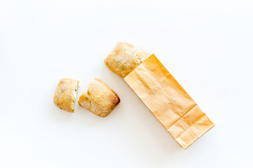 Fresh baguette and paper bag for bakery on white background top view