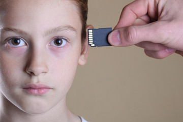 Kid inserting a memory card in her  head. Concept of memory upgrade or artificial intelligence