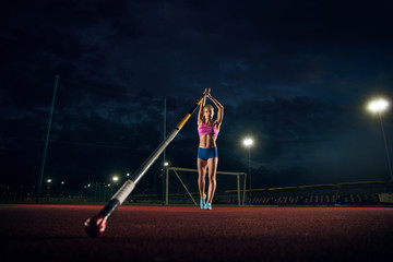 Ready to overcome difficulties. Professional female pole vaulter training at the stadium in the...