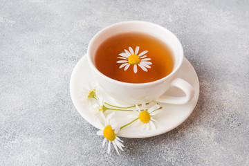 cup of herbal tea with chamomile flowers on grey table. Copy space