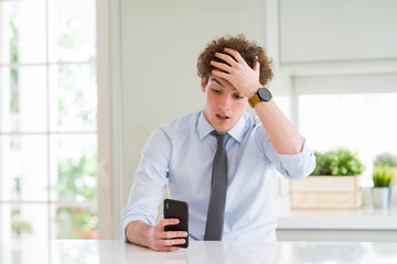 Young business man using smartphone at the office stressed with hand on head, shocked with shame...
