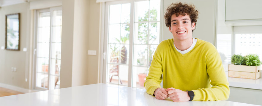 Wide angle shot of young handsome man at home with a happy and cool smile on face. Lucky person.