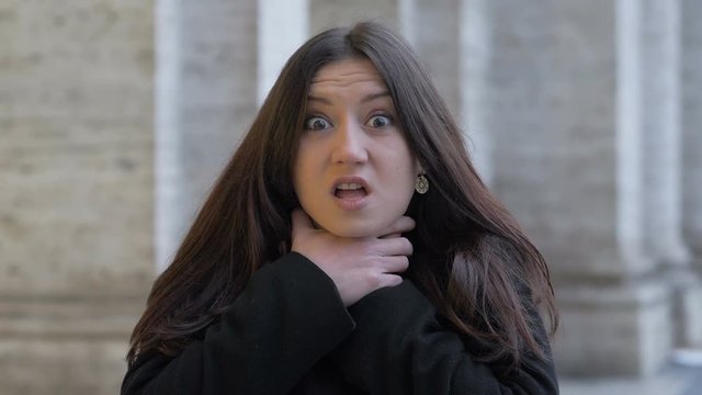young beautiful woman strangling herself with her hands in the street