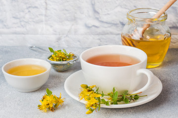 Cup with herbal tea from petals flowers Hypericum on grey background. Copy space.