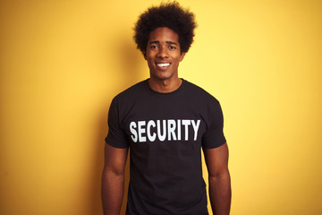 American safeguard man with afro hair wearing security uniform over isolated yellow background with...