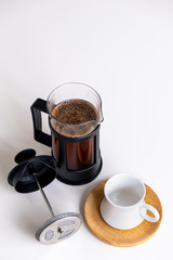 Coffee made with French press is ready to serve, white background.