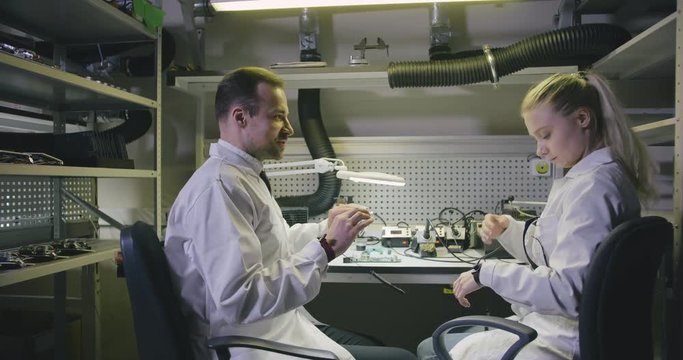 Two electronic engineers putting on protective glasses and start soldering motherboard